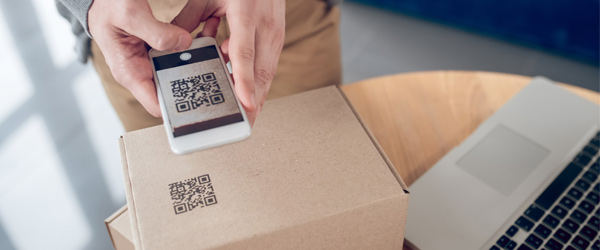 Persona escaneando código QR en una caja de cartón, ejemplo práctico de smart packaging aplicado a la cadena de suministro