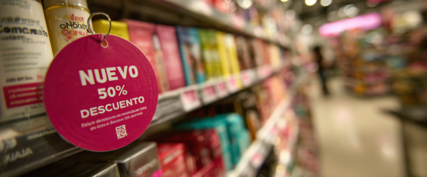 Primer plano de un wobbler publicitario redondo color fucsia en una estantería de supermercado, señalando un 50% de descuento sobre productos cosméticos. Ejemplo real de wobbler de cartón en el punto de venta