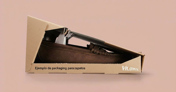 Caja triangular de cartón marrón reciclado mostrando un mocasín en su interior, ejemplo de packaging para zapatos creativo y reutilizable en diseño sostenible