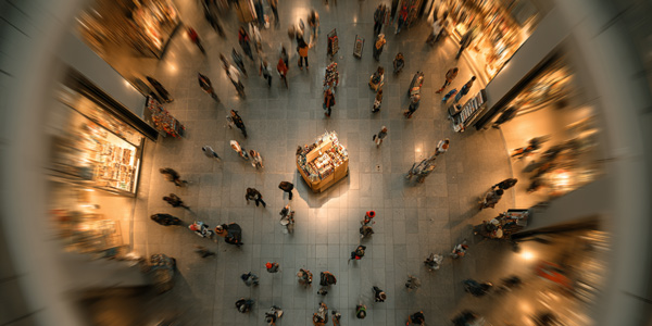 Vista cenital de un stand tipo isla promocional en el centro de una feria con alto tráfico de personas alrededor
