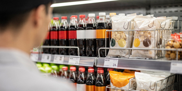 Expositor de cross merchandising en display PLV con bebidas y bolsas de snacks en primer plano