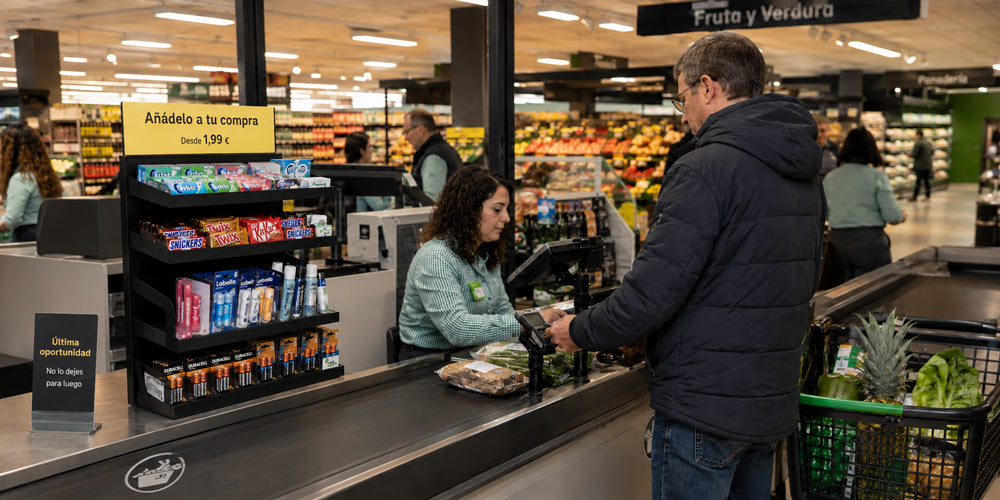 Expositor de impulso junto a la caja del supermercado con productos pequeños para añadir a la compra