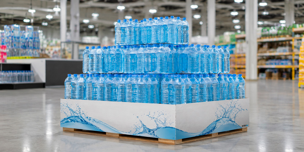 Isla PLV para bebidas con botellas de agua apiladas sobre palé en una gran superficie