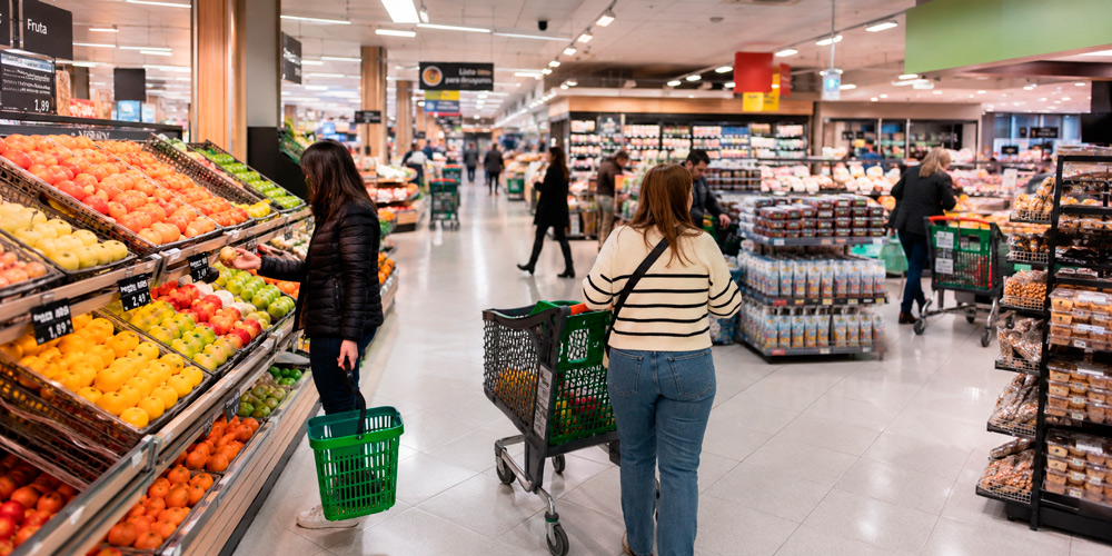 Clientes comprando en un supermercado con lineales, islas promocionales y diferentes zonas de paso