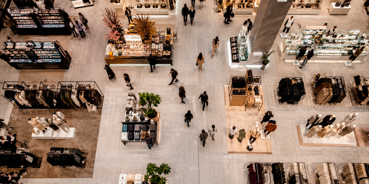Vista aérea de un gran espacio comercial con clientes, expositores y diferentes zonas de venta